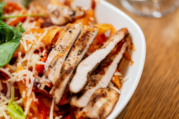 food and eating concept - close up of chicken pasta with cheese and vegetables on plate at restaurant