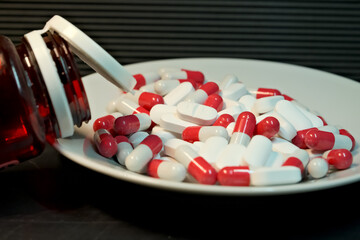 white and red pills in a plate. close-up. the concept of health, treatment.