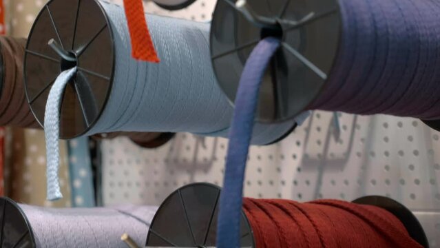 Large coils with ropes, laces of different colors on the stand in the store. Shot in motion. Macro. Closeup