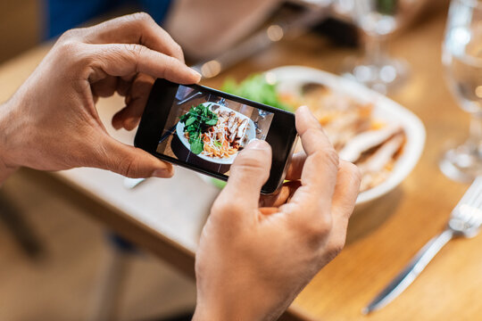 technology and people concept - close up of man with smartphone photographing food at restaurant
