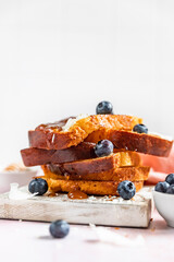 Stack of sweet french toasts with berries, caramel sauce and coconut flakes, pink background. Homemade brioche.