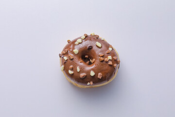 Ciambella con glassa al cioccolato e scaglie di cioccolato su superficie bianca