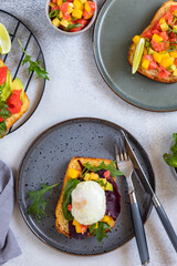 Assorted of open brioche sandwich with salmon, avocado, poached egg and mango salsa served with arugula and salad leaves. Healthy breakfast concept.