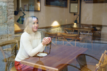 Through window of woman with coffee in cafe