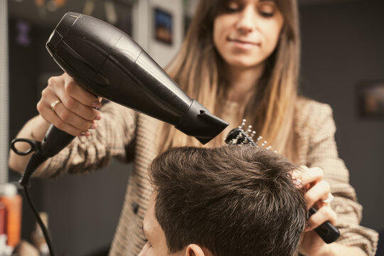 Hair salon master blow dry hair client at barber shop. Men's fashion and style. Hair care, beauty industry, barber concept. Barber shop men hairstyle. Young man getting a modern haircut