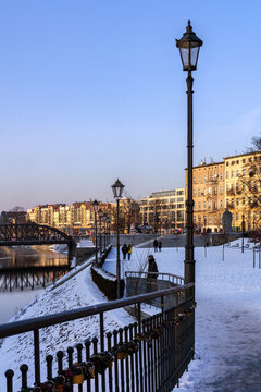 Walking trail in the city center of Wrocław in January, traditional streetlight and railing with padlocks 