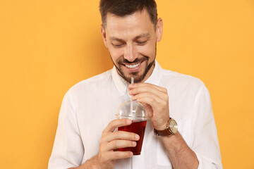 Man drinking delicious juice on orange background