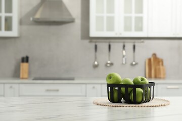 Fresh green apples on white table in kitchen, space for text