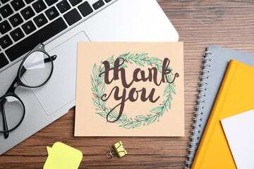Card with phrase Thank You, laptop, glasses and notebooks on wooden table, flat lay