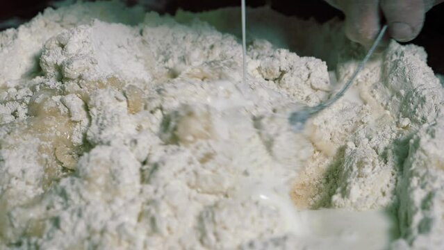 Adding kefir to flour for baking homemade balls of kolobok.