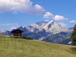 Fototapeta na wymiar In the foreground a mountain meadow with a mountain hut, in the background the Wetterstein Mountains