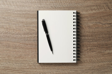 Notebook and pen on wooden table, top view