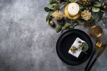 Christmas table setting with eucalyptus leaves and golden decorations. Top view at stone table. - obrazy, fototapety, plakaty