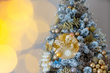 Close-up of a festively decorated outdoor Christmas tree with balls on a blurred sparkling fairy background. Defocused garland lights, bokeh effect.