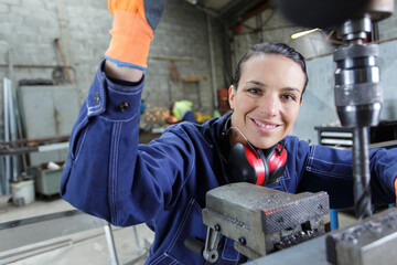 Fototapeta na wymiar female engineer using drill in factory