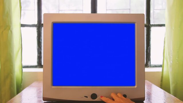 Female Hand Turning On Computer Monitor with Blue Screen. Close Up. 4K Resolution.