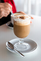 Cappuccino coffee in glass cup on white plate