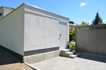 Rückseite einer modernen Beton-Garage mit Hintertür und benachbarte Gerätehütte auf dem...