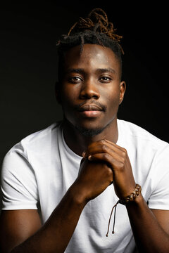 Dark studio portrait of black man in white shirt staring at camera