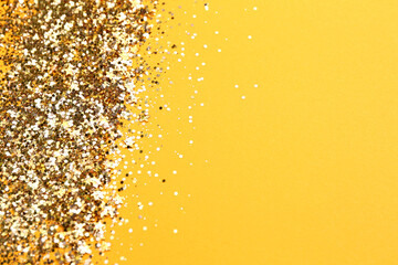 Shiny bright golden glitter on pale orange background. Space for text