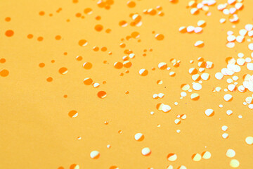 Fototapeta na wymiar Shiny bright orange glitter on yellow background
