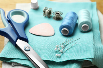 Scissors, spools of threads and sewing tools on table, closeup