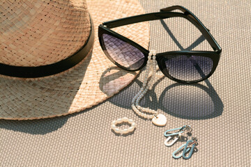 Stylish hat, sunglasses and jewelry on grey surface, closeup