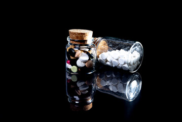 white orange pills in wineglass glass . in jar. in bucket Isolated on black set of capsule and pills inside closeup,