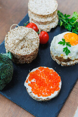 Diet rice breads, cherry tomatoes and fresh caviar and parsley on a dark background. Snack bread. View from above. Dietary fiber. Healthy Eating