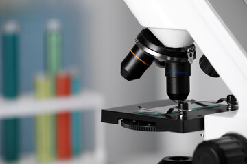 Modern medical microscope with glass slide on blurred background, closeup. Space for text