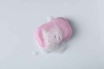 Soap with fluffy foam on white background, top view
