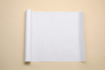 Roll of baking paper on beige background, top view