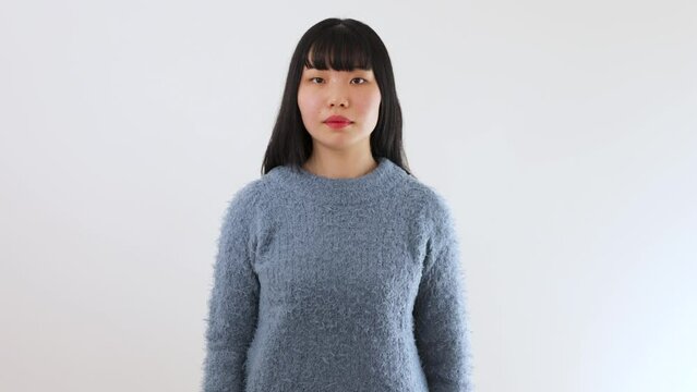 Young Japanese woman stands still with expressionless face.