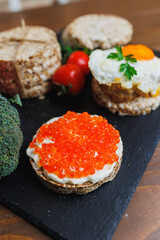 Diet rice breads, cherry tomatoes and fresh caviar and parsley on a dark background. Snack bread. View from above. Dietary fiber. Healthy Eating