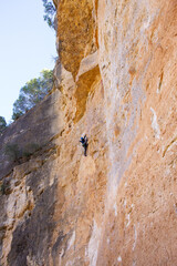 Young man climbing big rock wall in mountain