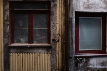 Old building facade domestic house with closed windows on restored dirty walls