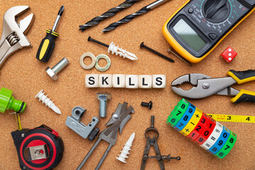 SKILLS word written on wood blocks. Various tools on cork background. business concept.