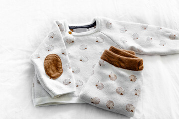 Muslin blanket, sweater, leggings, socks. Newborn baby clothes, accessories and toys set on neural white background. Fashion Scandinavian newborn essentials.