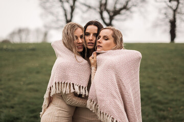 Close up Image of three sisters in wet clothes staying under water droplets at park.