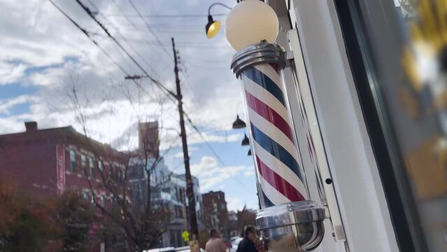A daytime exterior view of a spinning barber pole outside an establishment in a large city.	