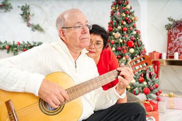 Father playing guitar during christmas. Happy man 60s playing guitar christmas songs. Happy...