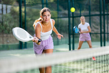 Padel game - woman with partners plays on the tennis court