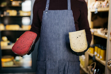 A man holds in hands different types of aged cheese at the cheese factory.