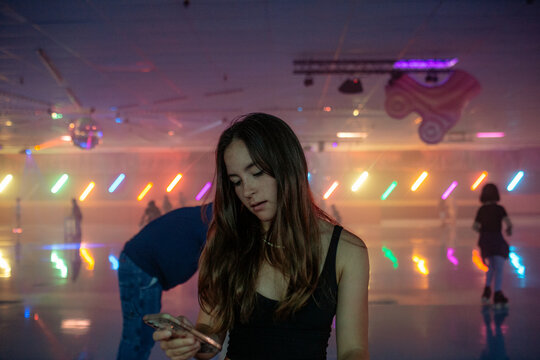 Teen girl looking at phone at roller skating rink