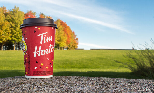Red Paper Tim Hortons cup of coffee Winning game cup autumn trees on background. Fresh morning coffee. Ottawa, ON, Canada - 20.10.2022