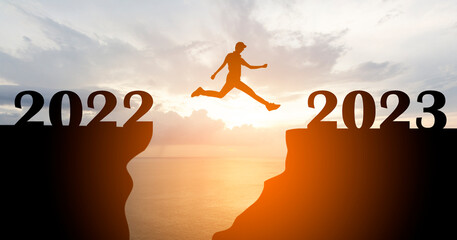 Silhouette of man jump to New year 2023 at sunrise with sea and beautiful sky, Happy New year 2023 concept	
