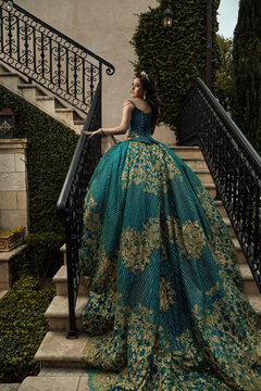 Female princess in green, emerald gold dress on stairs posing 