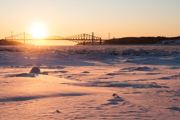 Old Quebec bridge in winter at sunset on beautiful day with clear sky. Snow and ice covering Saint-Lawrence River. L&eacute;vis, Quebec. Canada