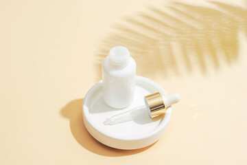 White dropper bottle with pipette and fern leaf shadow on beige background. Natural anti-aging cosmetics concept. Closeup