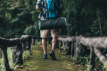 Hikers use trekking pole with backpacks and hold tent bag walking through the forest. hiking and adventure concept.